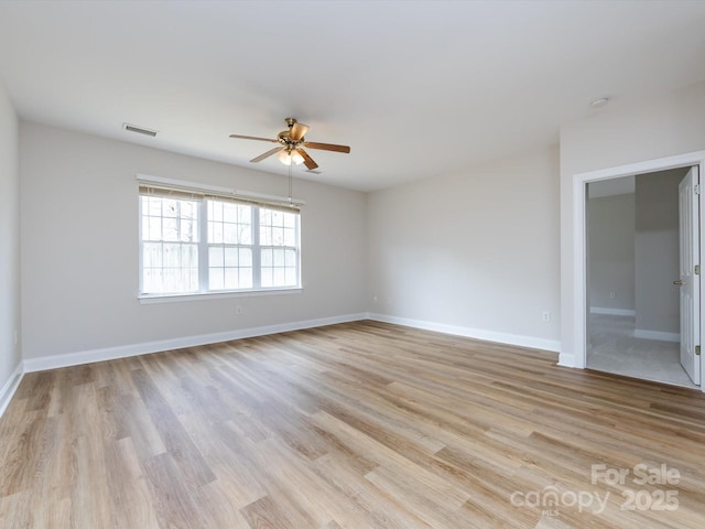 empty room with ceiling fan, light wood finished floors, visible vents, and baseboards