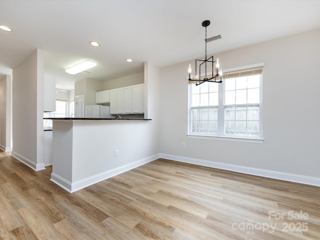 kitchen with light wood finished floors, dark countertops, recessed lighting, freestanding refrigerator, and baseboards