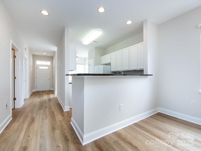 kitchen with dark countertops, recessed lighting, freestanding refrigerator, white cabinets, and light wood-type flooring