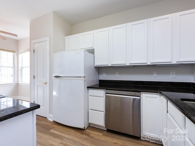 kitchen featuring stainless steel dishwasher, light wood-type flooring, freestanding refrigerator, and white cabinets