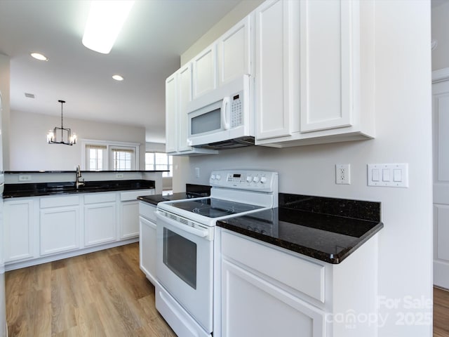 kitchen with light wood finished floors, white appliances, a sink, and white cabinetry