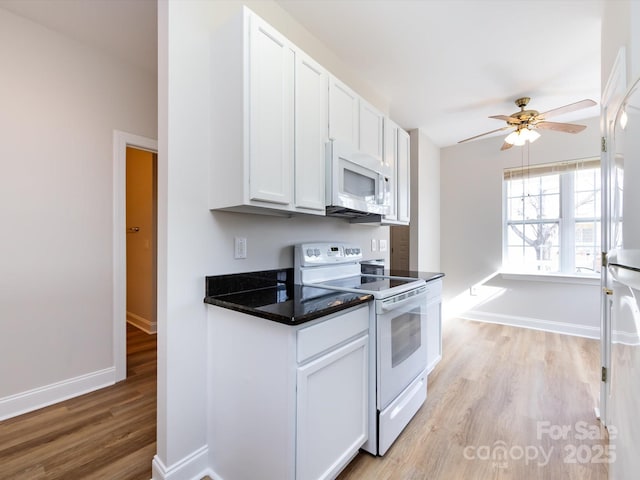 kitchen with white appliances, a ceiling fan, white cabinets, light wood-type flooring, and dark countertops