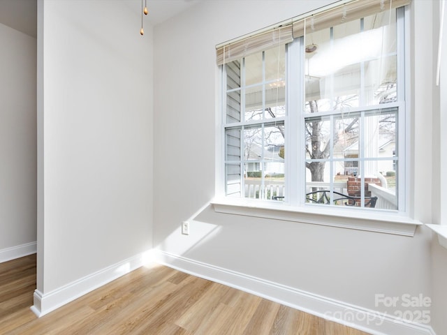 spare room featuring a healthy amount of sunlight, baseboards, and wood finished floors