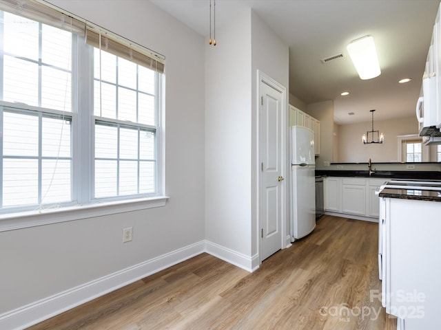 kitchen with visible vents, baseboards, light wood-type flooring, freestanding refrigerator, and dark countertops