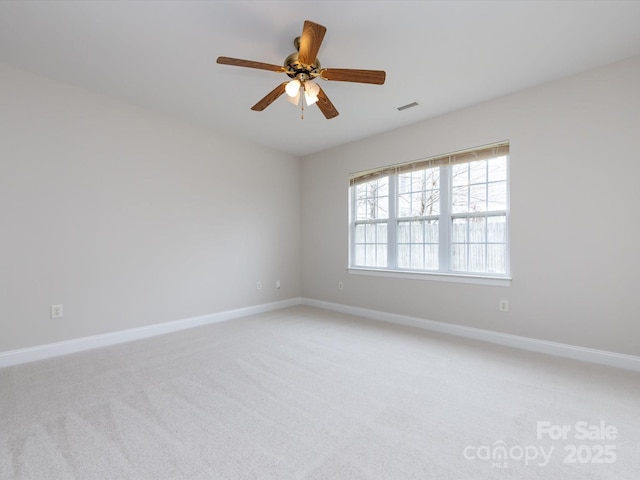 empty room featuring light carpet, a ceiling fan, visible vents, and baseboards