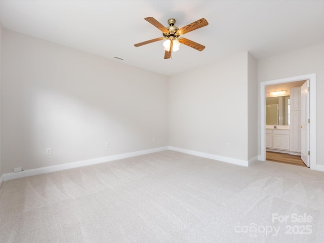 spare room with light carpet, ceiling fan, and baseboards