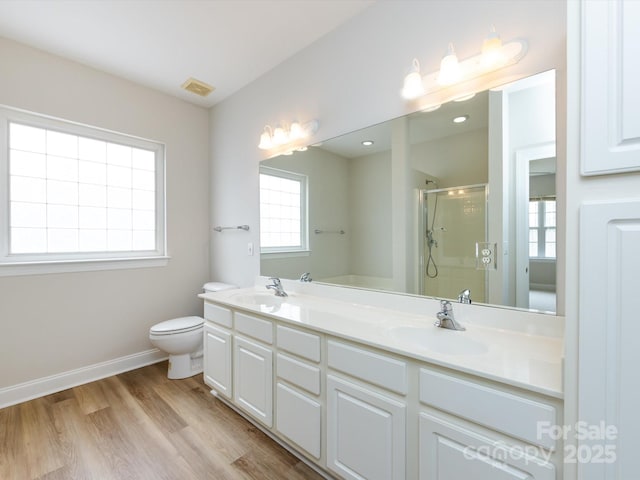 bathroom with double vanity, visible vents, wood finished floors, a shower stall, and a sink