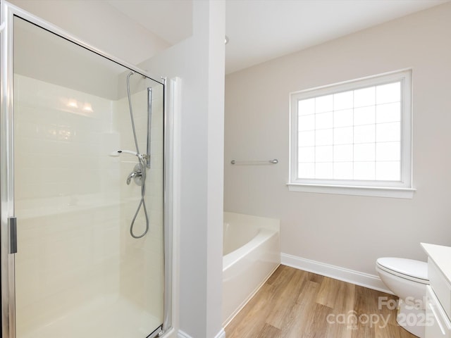 bathroom with wood finished floors, vanity, baseboards, a shower stall, and a bath