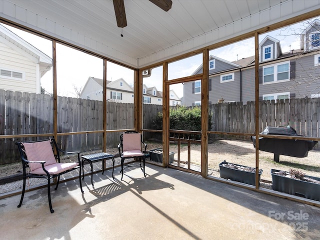 sunroom featuring ceiling fan and a residential view