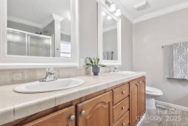 full bathroom with double vanity, ornamental molding, a stall shower, and a sink