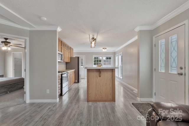 kitchen with open floor plan, light countertops, a textured ceiling, stainless steel appliances, and crown molding