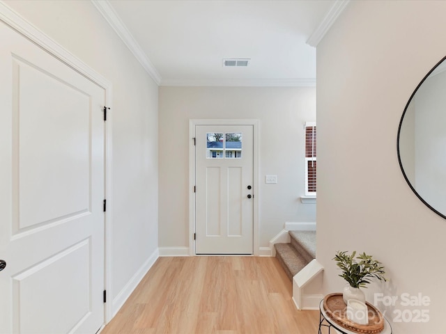 foyer entrance featuring visible vents, stairway, baseboards, light wood finished floors, and ornamental molding