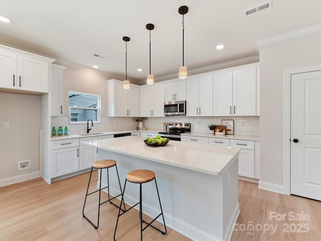 kitchen featuring white cabinets, appliances with stainless steel finishes, a sink, and visible vents