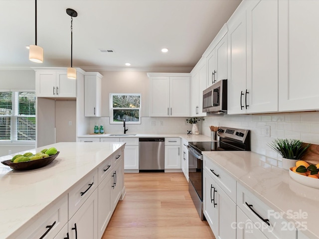 kitchen with crown molding, a healthy amount of sunlight, white cabinetry, a sink, and stainless steel appliances