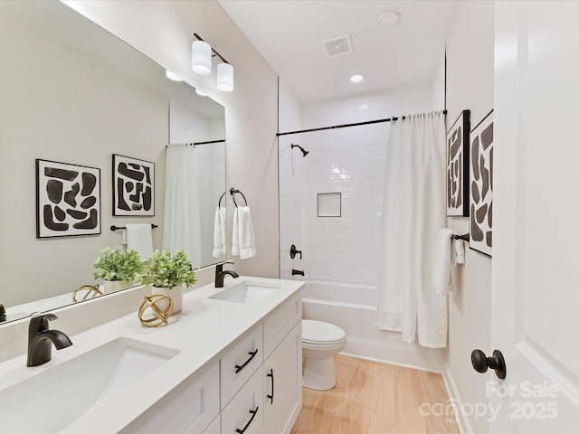 bathroom featuring shower / bath combo with shower curtain, a sink, wood finished floors, and toilet