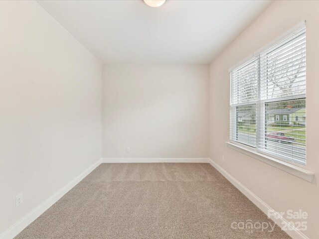 unfurnished room with light colored carpet and baseboards
