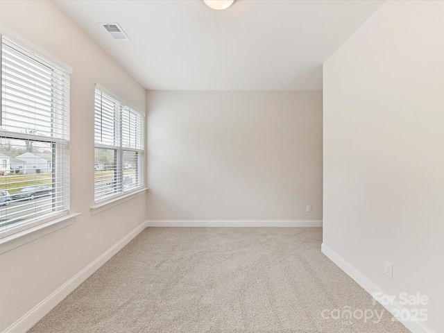 carpeted empty room featuring baseboards and visible vents