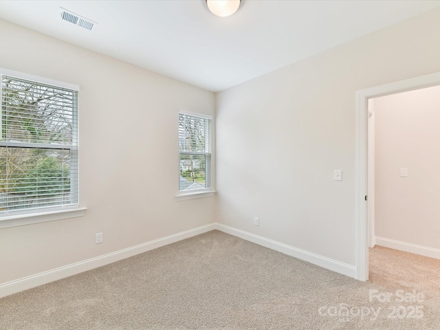 spare room with baseboards, visible vents, and carpet