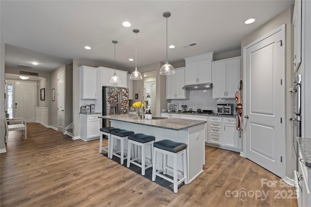 kitchen featuring visible vents, light wood-style flooring, appliances with stainless steel finishes, a sink, and under cabinet range hood