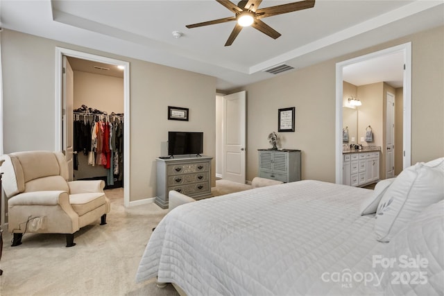 bedroom featuring light carpet, visible vents, a spacious closet, a closet, and a tray ceiling