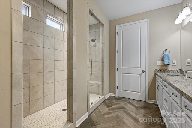 full bathroom with a shower stall, vanity, and baseboards