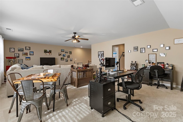 office space featuring a ceiling fan, visible vents, vaulted ceiling, and light carpet