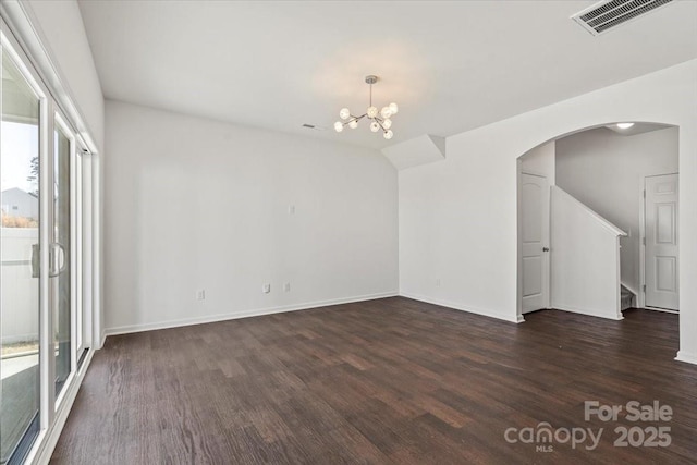 empty room with baseboards, visible vents, arched walkways, dark wood-style flooring, and a chandelier