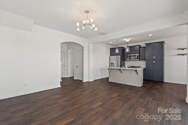 kitchen with light countertops, appliances with stainless steel finishes, dark wood-style flooring, and a breakfast bar