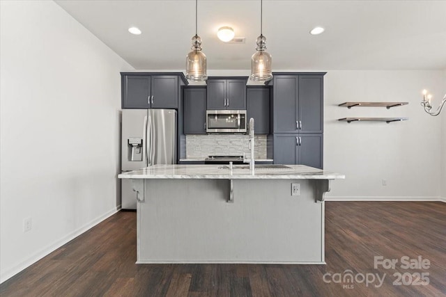 kitchen with a breakfast bar area, stainless steel appliances, backsplash, a kitchen island with sink, and a sink