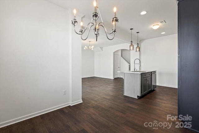 kitchen featuring arched walkways, dark wood-type flooring, a sink, light countertops, and a notable chandelier