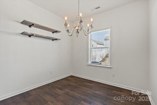 empty room with an inviting chandelier, visible vents, baseboards, and wood finished floors