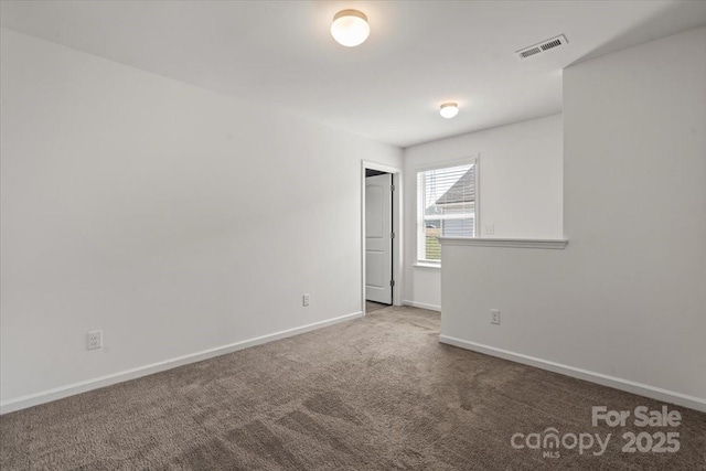 spare room featuring carpet, visible vents, and baseboards