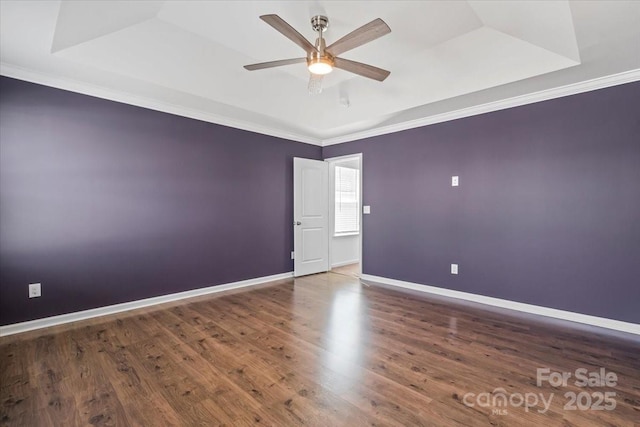 spare room featuring ornamental molding, a tray ceiling, baseboards, and a ceiling fan