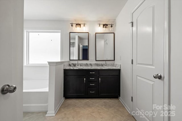 bathroom with double vanity, baseboards, a bathtub, and a sink