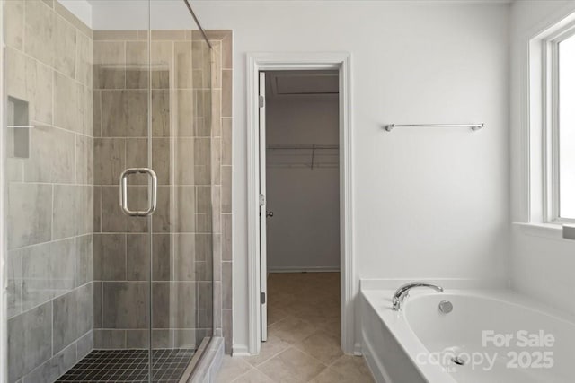 bathroom featuring a shower stall, a spacious closet, a bath, and tile patterned floors