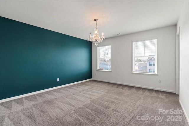 carpeted spare room featuring an inviting chandelier, visible vents, and baseboards