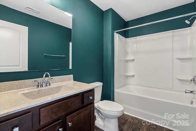 full bathroom featuring visible vents, toilet, vanity, wood finished floors, and shower / bathtub combination