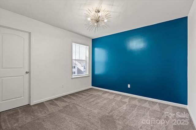 carpeted spare room featuring an inviting chandelier and baseboards