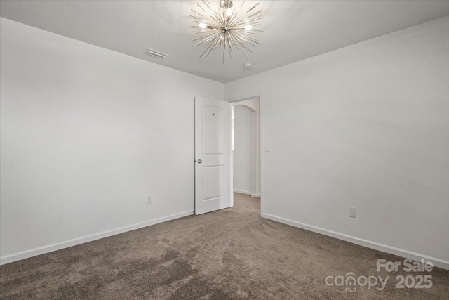 empty room featuring carpet floors, an inviting chandelier, baseboards, and visible vents