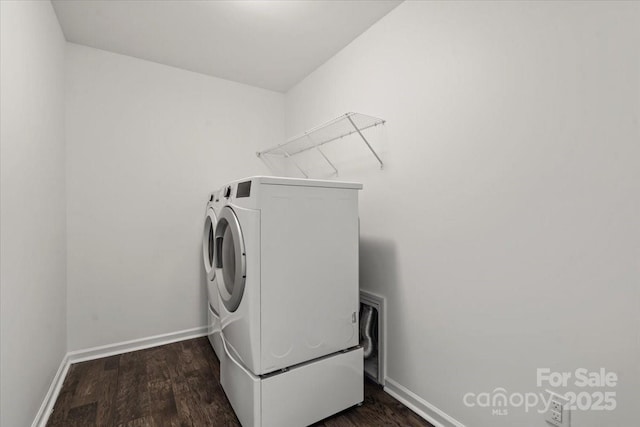 clothes washing area with dark wood finished floors, laundry area, independent washer and dryer, and baseboards