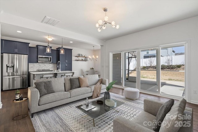 living room with visible vents, recessed lighting, dark wood-style flooring, and a chandelier
