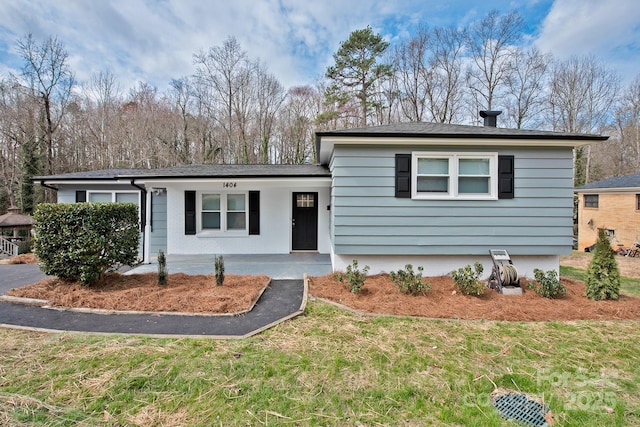 view of front of property featuring a front yard, covered porch, and driveway