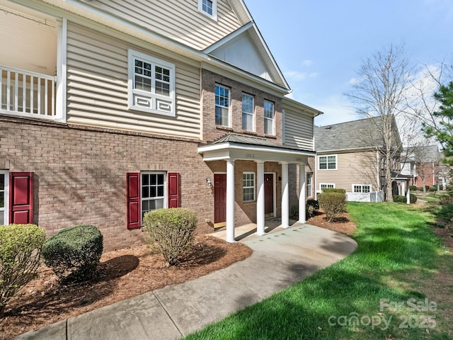 exterior space featuring covered porch, brick siding, and a lawn