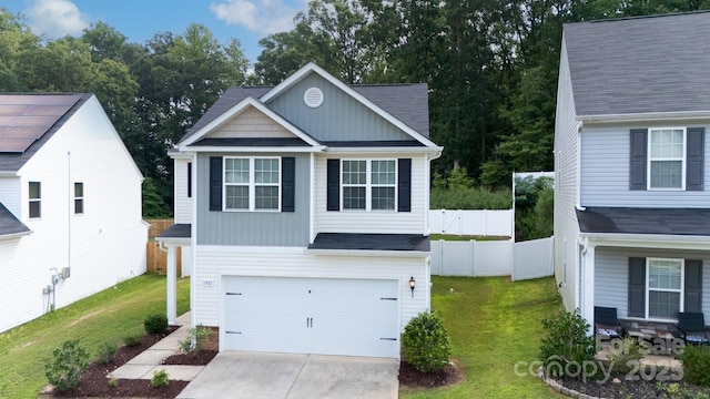 view of front facade with an attached garage, driveway, a front lawn, and fence