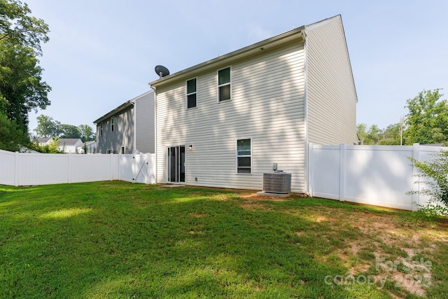 rear view of property featuring a yard, a fenced backyard, and cooling unit