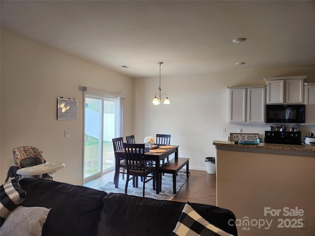 dining area featuring dark wood-style floors, visible vents, a notable chandelier, and baseboards