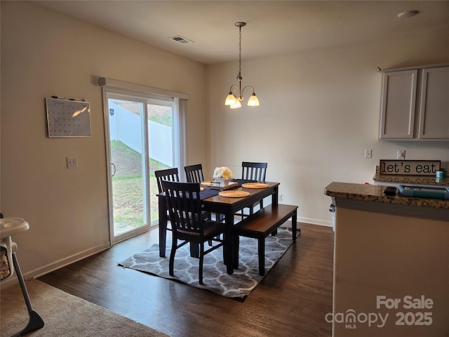 dining space with baseboards, dark wood-style flooring, visible vents, and a notable chandelier