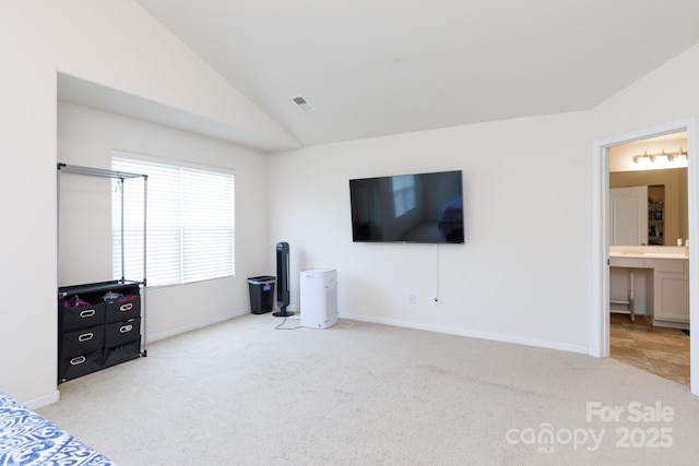 unfurnished bedroom with lofted ceiling, light carpet, visible vents, baseboards, and ensuite bath