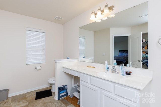 bathroom with toilet, vanity, visible vents, and baseboards