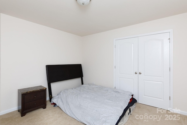 bedroom with light carpet, baseboards, and a closet